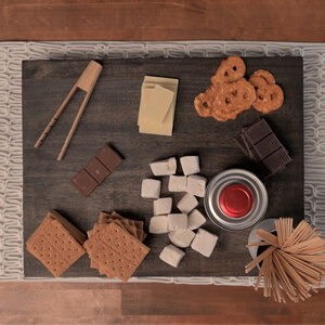 Crackers, cheese cubes and other snacks on a stained wood charcuterie board.